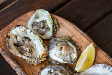 Oysters with lemon on wooden plate.