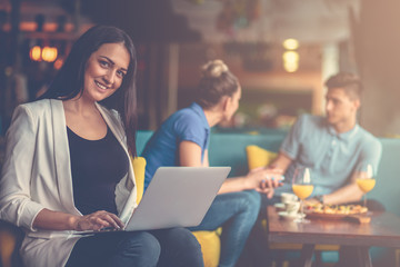 Young female student is using laptop computer in cafe