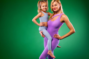 Hatha yoga fitness . Young mother and daughter exercise together indoors. Family look.