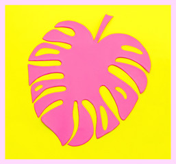 Pink tropical Monstera leaf from paper on yellow background. Fashion minimal pop art style.