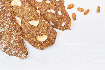 Bread with flaxseeds and almonds on a white wooden background. Useful dietary raw bread vegan breakfast without yeast