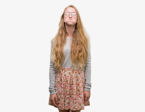 Blonde teenager woman wearing flowers skirt puffing cheeks with funny face. Mouth inflated with air, crazy expression.