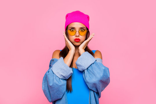Close up portrait of  funny, foolish and young girl puffed her cheeks and hold them with her hands isolated on vivid pink background