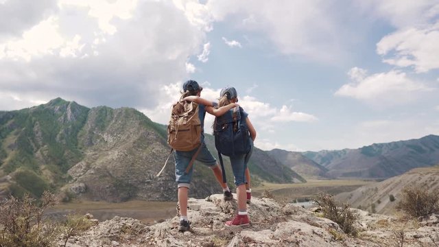 children of the travelers embrace and enjoy the beautiful view of the mountains. two little girls with backpacks on a hike