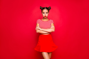 Comedian humor joke concept. Portrait of grimacing funny capricious young woman model with bun hairstyle holding air in cheeks isolated on red background