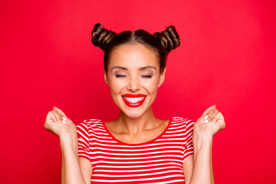 Close up portrait of happy young woman with toothy smile clasp hands in fists and celebrate achievement goal isolated on red bright background