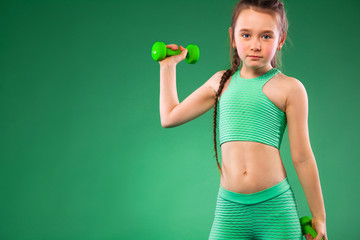 Kid girl doing fitness exercises on green background
