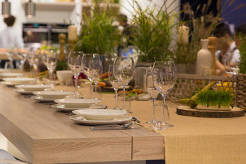 Empty wine glasses near the plates  on the table with  greenery