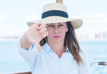 Beautiful middle age woman traveling on sailboat with angry face, negative sign showing dislike with thumbs down, rejection concept