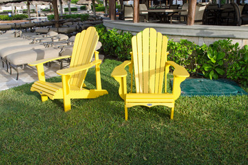 Yellow chairs in park. Grass, poolside