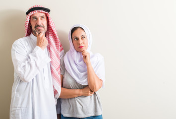 Middle age arabic couple, woman and man serious face thinking about question, very confused idea