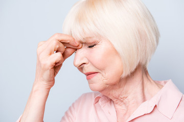 Close up portrait of old adult caucasian lady feeling head ache, pain, high blood pressure facial...