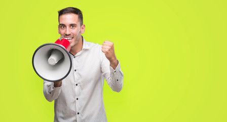 Handsome young man holding microphone screaming proud and celebrating victory and success very excited, cheering emotion