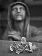 Blurred sculpture of a grieving woman over a grave in with a dry leaves in the foreground