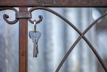A bunch of keys hanging on the rusted fence of the grave in the cemetery