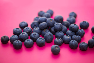Group of ripe and juicy blue on a color pink background, close-up of berries, selective focus