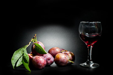 Plums ripe and juicy shot close-up on a dark background and a glass of wine