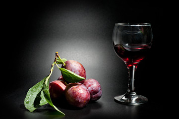 Plums ripe and juicy shot close-up on a dark background and a glass of wine