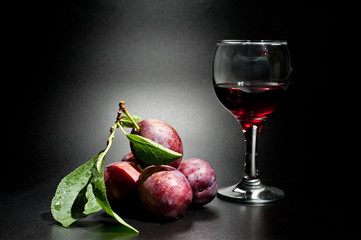 Plums ripe and juicy shot close-up on a dark background and a glass of wine