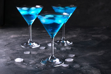Blue cold cocktails  drink with ice cubes  on a dark background