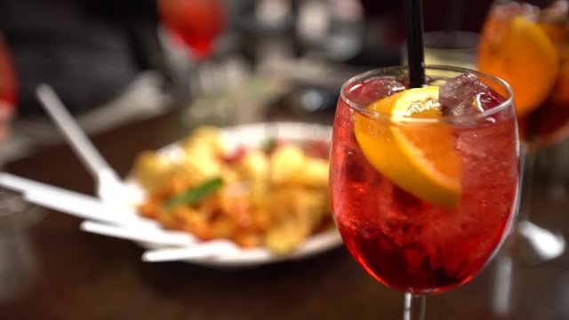 4K, Glasses of sparkling wine with aperol cocktail and appetizer platter with chips fried potatoes and pasta on the table at restaurant. Italian aperitives at outdoor bar in the street of Italy-Dan