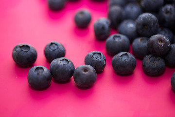 Group of blueberries on a pink background close-up.