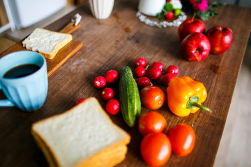 Summer breakfast, radish, tomatoes, cucumber and pepper on wooden board. Coffee cup with toast