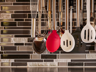 Assortment of kitchen gadgets hanging in front of a mosaic tiled wall