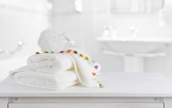 White cotton towels on wooden counter table inside bright bathroom