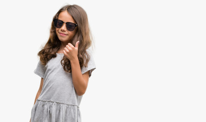 Naklejka premium Brunette hispanic girl wearing sunglasses doing happy thumbs up gesture with hand. Approving expression looking at the camera with showing success.