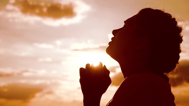 the girl prays lifestyle. Girl folded her hands in prayer silhouette at sunset. slow motion video. Girl folded her hands in prayer pray to God. girl praying asks forgiveness for sins of repentance