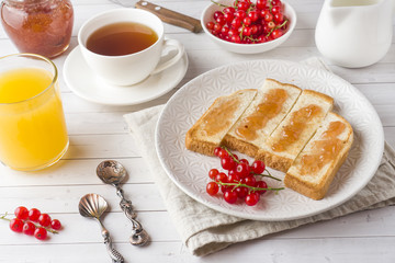 Healthy Breakfast with toast, jam, fresh orange juice and red currants, a Cup of coffee on the white table.