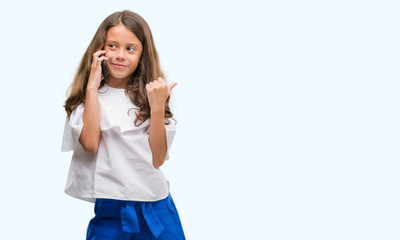 Obraz premium Brunette hispanic girl using smartphone pointing and showing with thumb up to the side with happy face smiling