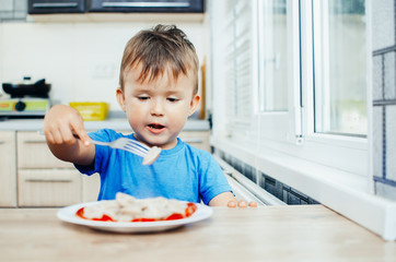 A hungry child is eating dumplings in the kitchen