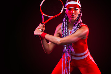 Tennis player. Beautiful woman athlete with racket in red costume and hat isolated on black background. Fashion and sport concept.