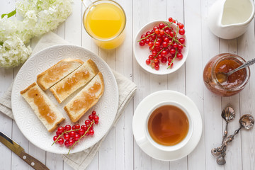 Fototapeta na wymiar Healthy Breakfast with toast, jam, fresh orange juice and red currants, a Cup of coffee on the white table.