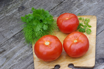 Tomatoes, parsley and dill on a cutting board