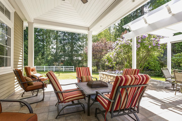 Spacious covered deck patio with table and red chairs.