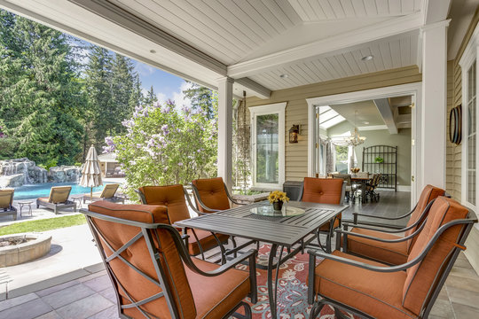 Spacious covered deck patio with table and red chairs.