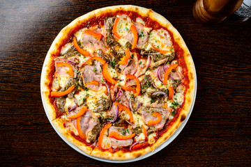 Tasty warm pizza with bacon, pepper, cheese and onion on the tab