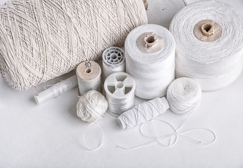 Fototapeta na wymiar different types of white threads cotton, elastic band, flax, plait, mouline thread, silk