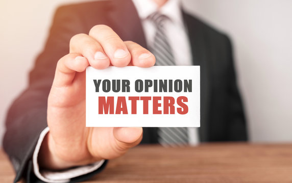 Businessman holding a card with text Your Opinion Matters