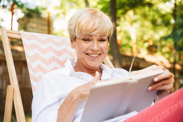 Smiling mature woman reading a book while resting