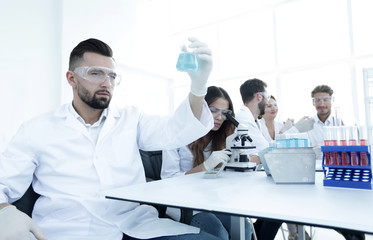 biochemist with flask Petri sitting at a Desk