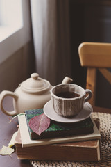 Fototapeta na wymiar cozy autumn morning at country house, cup of tea and books on wooden table. Still life details