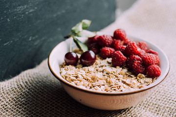 Delicious, healthy breakfast.Porridge with berries.Ecofriendly.Oatmeal porridge with raspberries and cherries.The idea for breakfast on black background. Natural, dietary food.Good morning. Life style