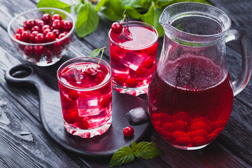 Red cherry cocktail with ice and fresh mint on a black wooden table. refreshing summer drink