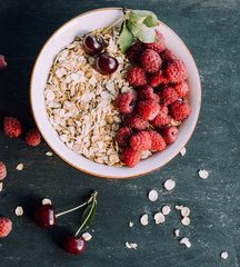 Delicious, healthy breakfast.Porridge with berries.Ecofriendly.Oatmeal porridge with raspberries and cherries.The idea for breakfast on black background. Natural, dietary food.Good morning. Life style