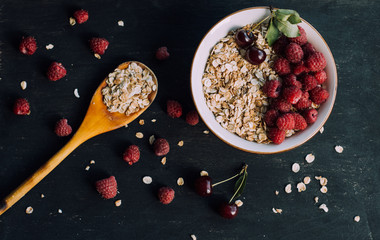 Delicious, healthy breakfast.Porridge with berries.Ecofriendly.Oatmeal porridge with raspberries and cherries.The idea for breakfast on black background. Natural, dietary food.Good morning. Life style