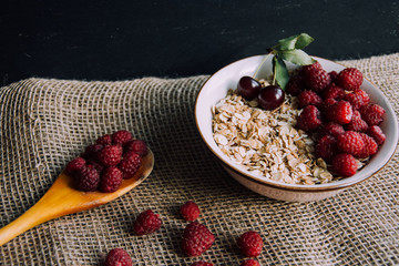 Delicious, healthy breakfast.Porridge with berries.Ecofriendly.Oatmeal porridge with raspberries and cherries.The idea for breakfast on black background. Natural, dietary food.Good morning. Life style